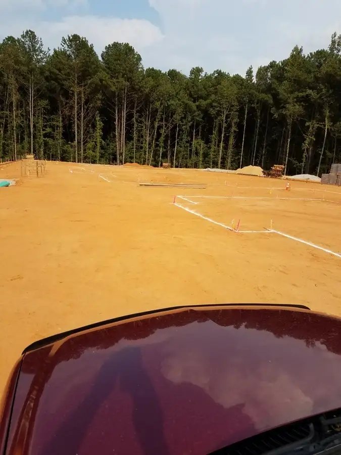 Graded building pad with layout lines and stakes at a construction site