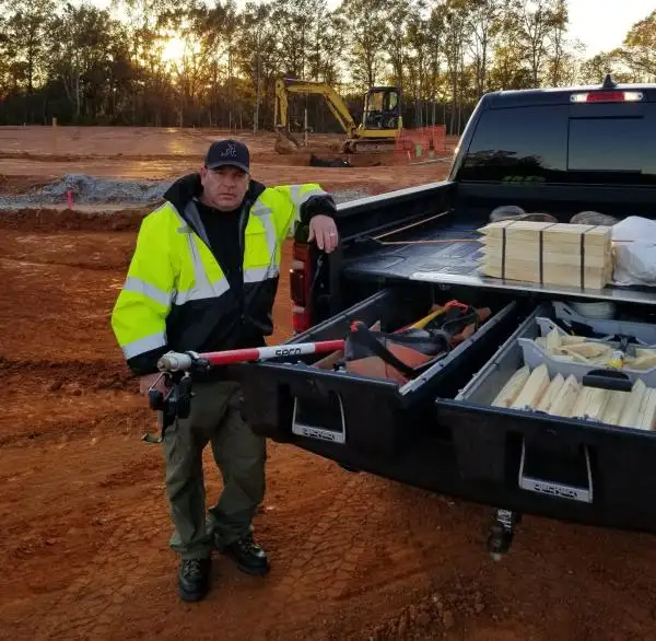 Randy Phillips, PLS, with survey stakes in his truck on a construction site at sunset